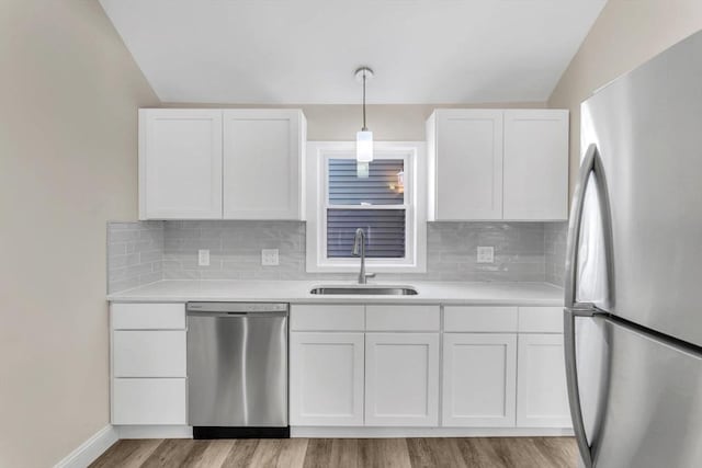 kitchen with lofted ceiling, white cabinets, sink, decorative light fixtures, and stainless steel appliances