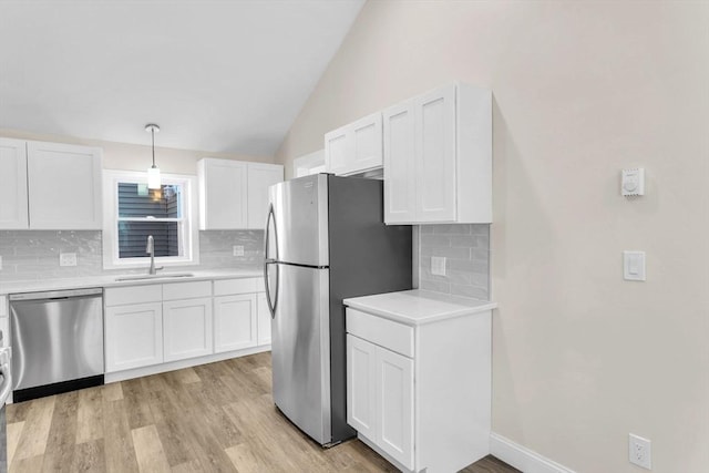 kitchen with appliances with stainless steel finishes, white cabinetry, lofted ceiling, and sink