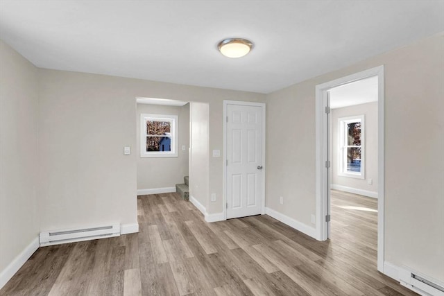 unfurnished room featuring baseboard heating and light hardwood / wood-style flooring