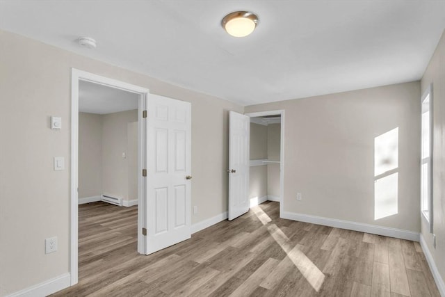 unfurnished bedroom with light hardwood / wood-style floors and baseboard heating