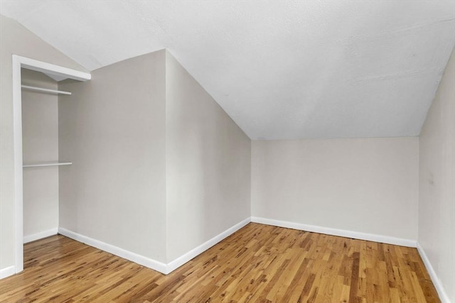 additional living space featuring wood-type flooring and vaulted ceiling