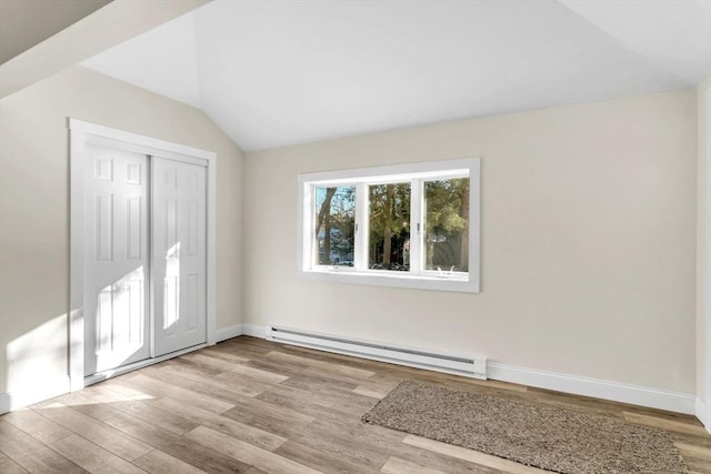 interior space with vaulted ceiling, light wood-type flooring, and a baseboard radiator