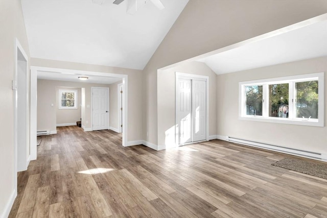 interior space with ceiling fan, light wood-type flooring, lofted ceiling, and a baseboard radiator