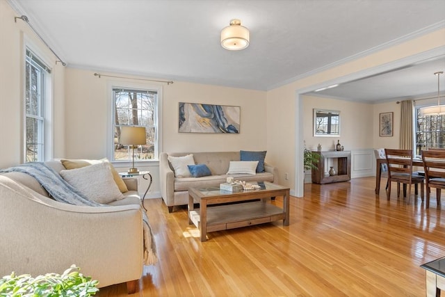 living area with baseboards, light wood finished floors, and ornamental molding