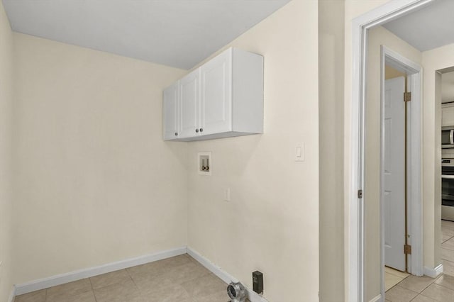 clothes washing area featuring cabinets, washer hookup, and light tile patterned floors