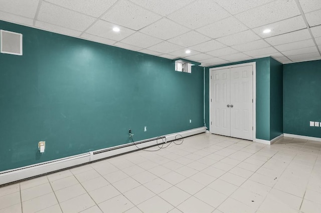 basement featuring a baseboard radiator and a paneled ceiling