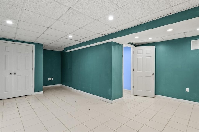 basement with a drop ceiling and light tile patterned floors