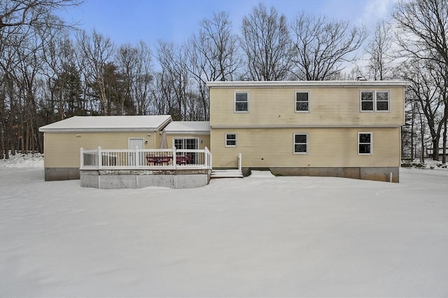 snow covered back of property featuring a deck