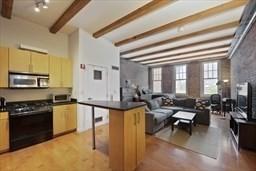 26 Stillman St Unit 4-5, Boston, MA 02113 - kitchen featuring a breakfast bar area, gas range oven, stainless steel microwave, dark countertops, and beam ceiling