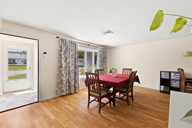 dining space featuring light wood-style flooring and baseboards