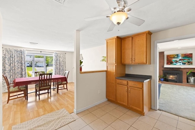 kitchen featuring dark countertops, baseboards, ceiling fan, brown cabinetry, and open floor plan