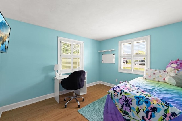 bedroom featuring wood finished floors, multiple windows, and baseboards