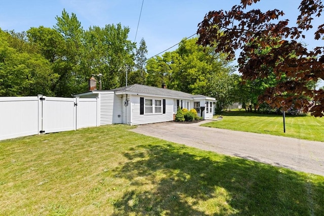 view of front of house featuring a gate, a chimney, and asphalt driveway