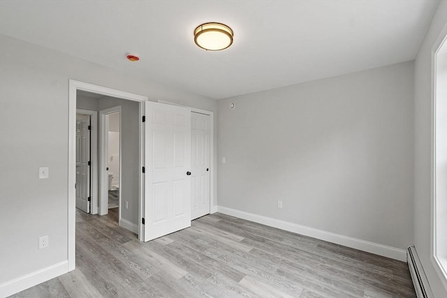 572 Pleasant St, Athol, MA 01331 - unfurnished bedroom featuring a baseboard radiator, light wood-style floors, and a closet