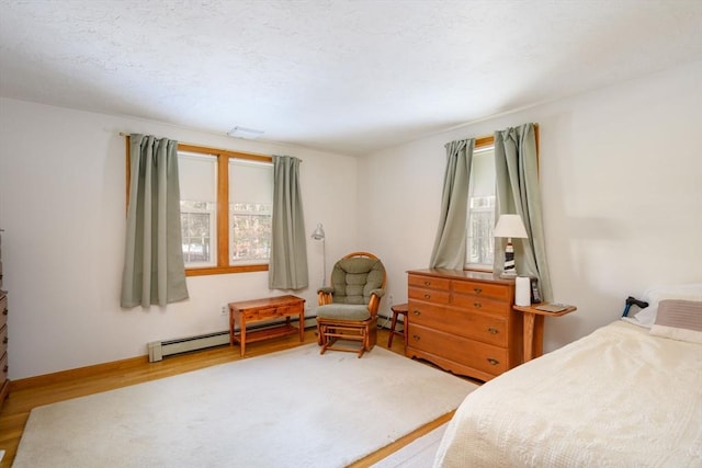 bedroom with hardwood / wood-style floors and a baseboard heating unit