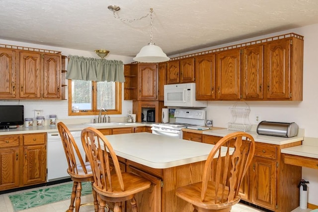 kitchen featuring a kitchen island, sink, a breakfast bar area, hanging light fixtures, and white appliances