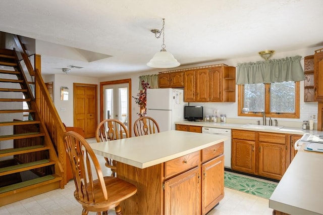 kitchen with sink, decorative light fixtures, a center island, white appliances, and a healthy amount of sunlight