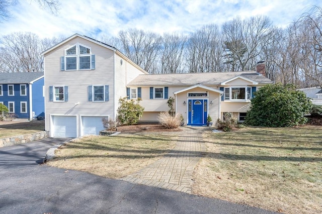 view of front of home with driveway, an attached garage, and a front yard