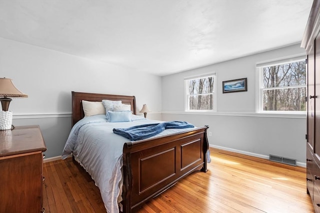 bedroom with light wood-style flooring, baseboards, and visible vents