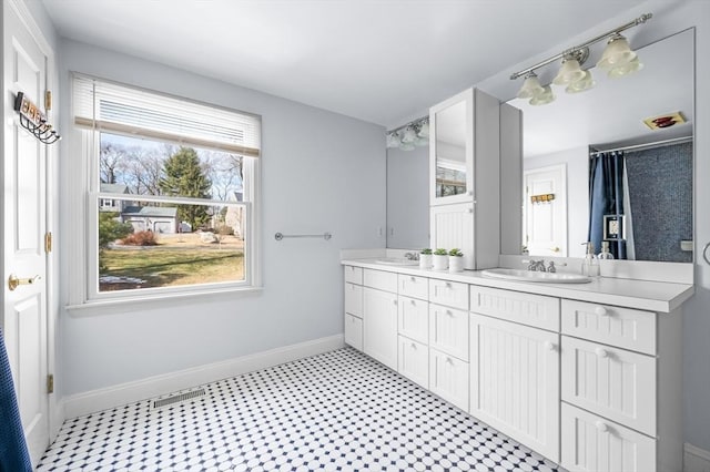 bathroom featuring double vanity, baseboards, tile patterned floors, and a sink