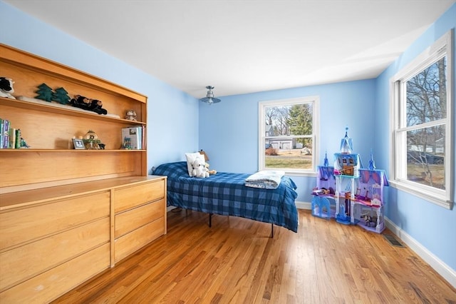 bedroom featuring visible vents, light wood-style floors, and baseboards