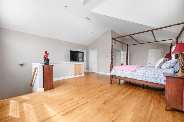 bedroom featuring visible vents, baseboards, light wood-type flooring, and lofted ceiling