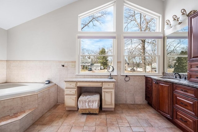 full bathroom featuring tiled bath, lofted ceiling, tile walls, and vanity