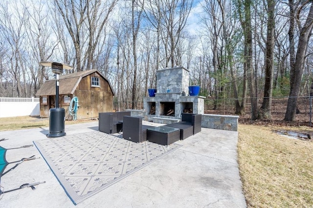 view of patio / terrace featuring an outdoor structure, an outdoor living space with a fireplace, and fence