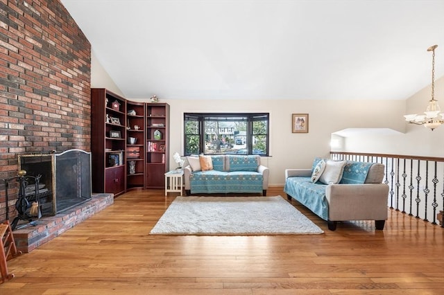 living area with lofted ceiling, a chandelier, a fireplace, and light wood finished floors