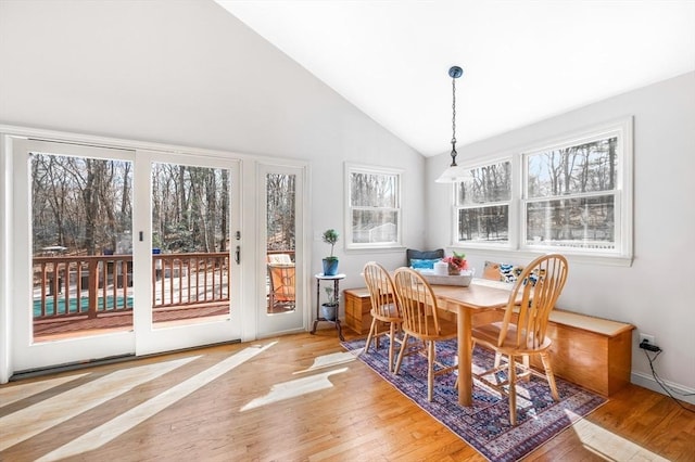 dining space featuring light wood-type flooring and high vaulted ceiling