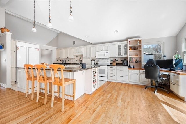 kitchen with white appliances, dark countertops, light wood-style floors, and lofted ceiling