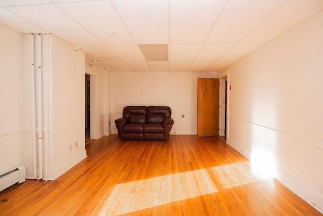 unfurnished room featuring hardwood / wood-style floors, a paneled ceiling, and a baseboard radiator