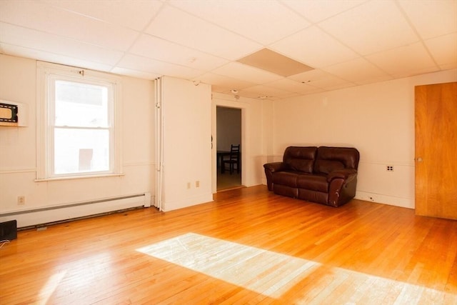 unfurnished room with hardwood / wood-style flooring, a drop ceiling, and a baseboard heating unit