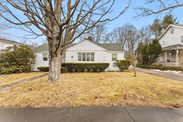 view of front of property featuring a chimney, a front lawn, and stucco siding