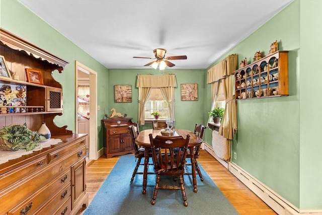 dining room featuring light wood finished floors, ceiling fan, baseboards, and baseboard heating