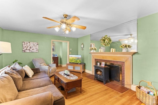 living room with a ceiling fan, baseboards, and wood finished floors