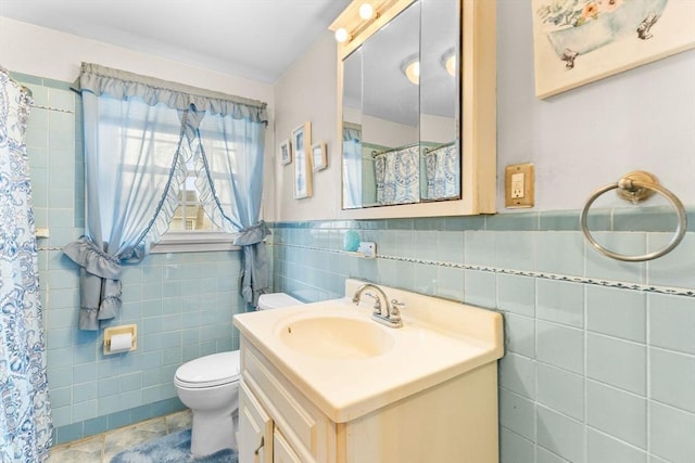 full bathroom featuring toilet, a shower with shower curtain, vanity, tile walls, and wainscoting