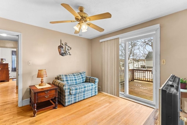 sitting room with ceiling fan, a baseboard radiator, wood finished floors, and baseboards