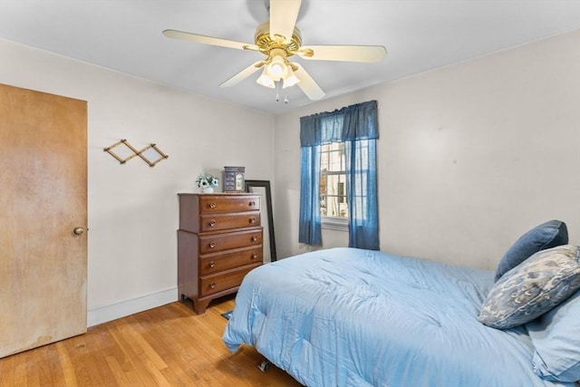 bedroom with wood-type flooring, a ceiling fan, and baseboards