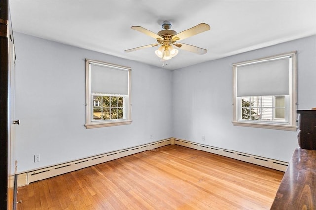 spare room with a baseboard heating unit, ceiling fan, and wood finished floors