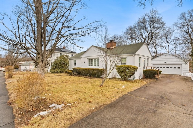 view of front of property featuring a garage, stucco siding, a chimney, and an outdoor structure