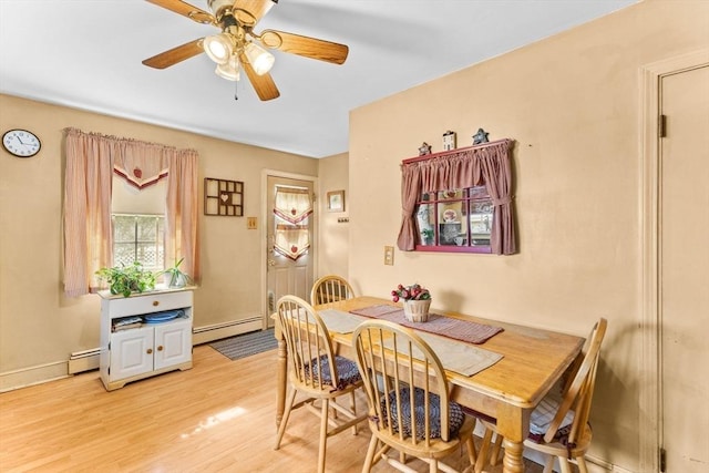 dining area with a baseboard heating unit, light wood-type flooring, a ceiling fan, and baseboards