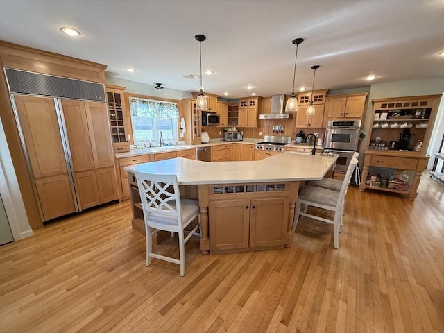 74 Fiske Hill Rd, Sturbridge, MA 01566 - kitchen with appliances with stainless steel finishes, wall chimney range hood, light countertops, light wood-style flooring, and a kitchen bar