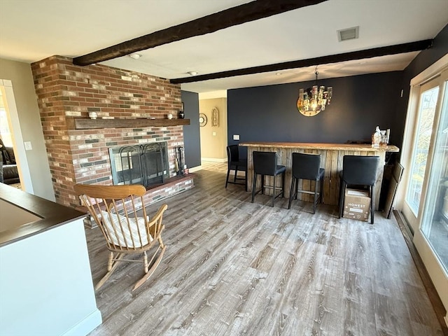 74 Fiske Hill Rd, Sturbridge, MA 01566 - dining room featuring wood finished floors, beam ceiling, a chandelier, a brick fireplace, and baseboards