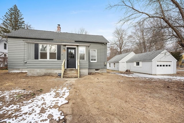 bungalow-style home with a garage and an outbuilding