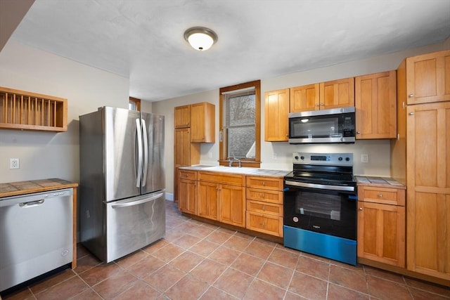 kitchen featuring appliances with stainless steel finishes, tile countertops, and sink