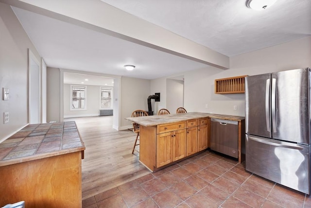 kitchen featuring hardwood / wood-style floors, appliances with stainless steel finishes, a kitchen bar, and kitchen peninsula