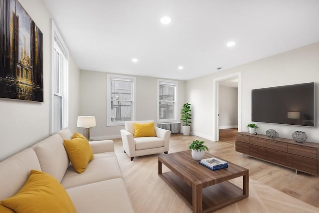 living room with radiator heating unit, a healthy amount of sunlight, and light wood-type flooring