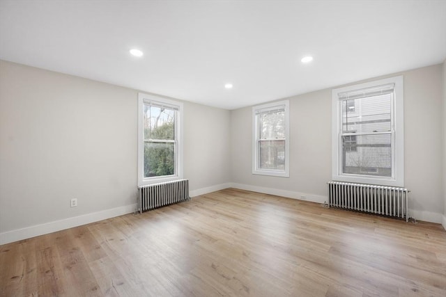 empty room featuring radiator and light hardwood / wood-style flooring