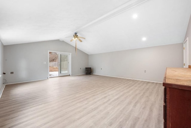 unfurnished living room featuring ceiling fan, vaulted ceiling, light wood-type flooring, and a wood stove